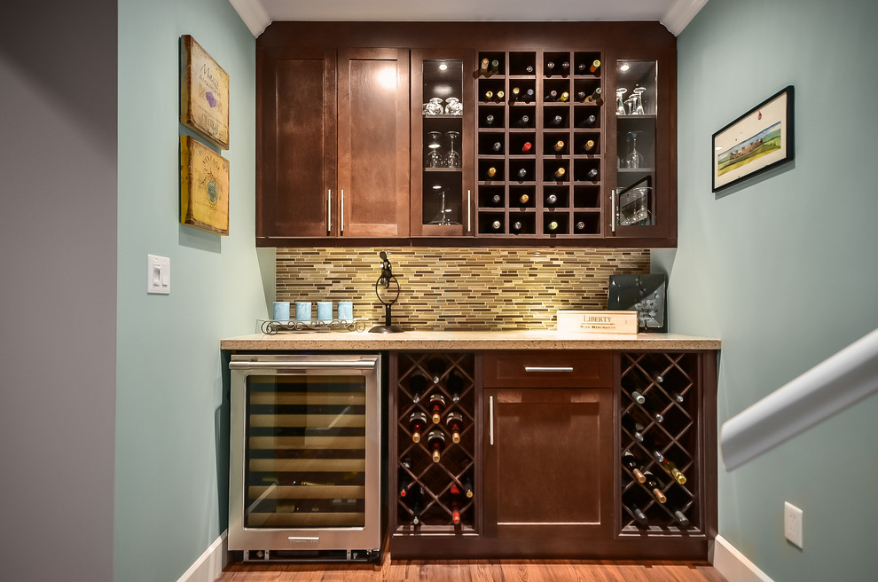 This is an example of a traditional single-wall home bar in Vancouver with shaker cabinets, dark wood cabinets, brown splashback, matchstick tile splashback, dark hardwood floors and brown floor.