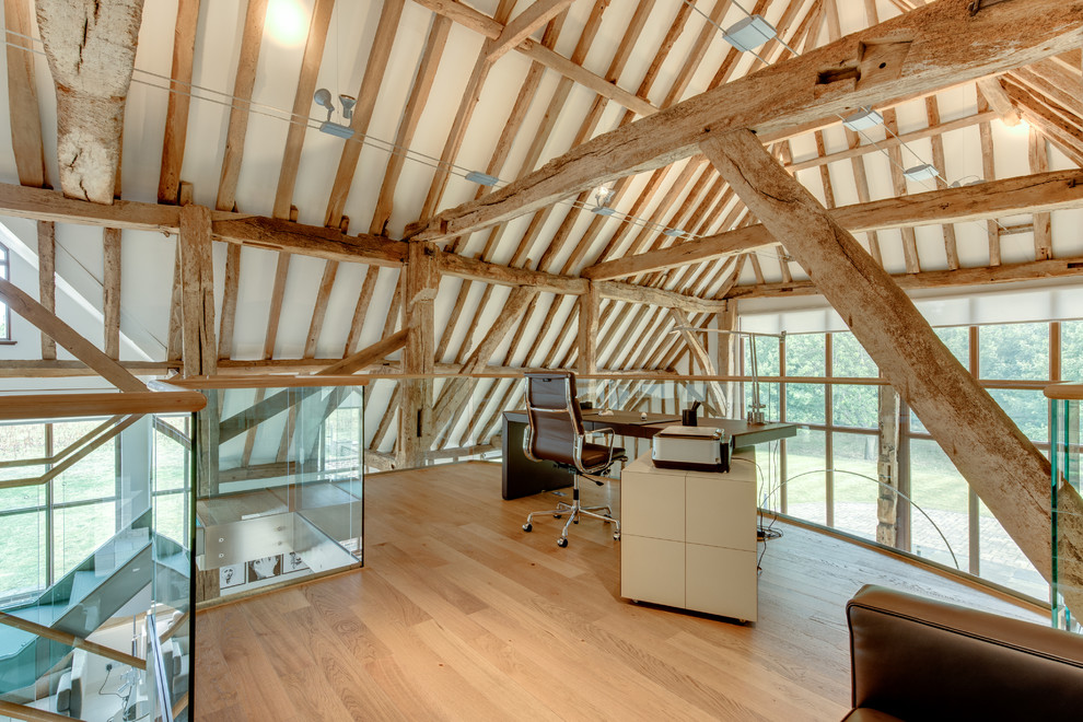 Photo of a country study room in Other with light hardwood floors, a freestanding desk and white walls.
