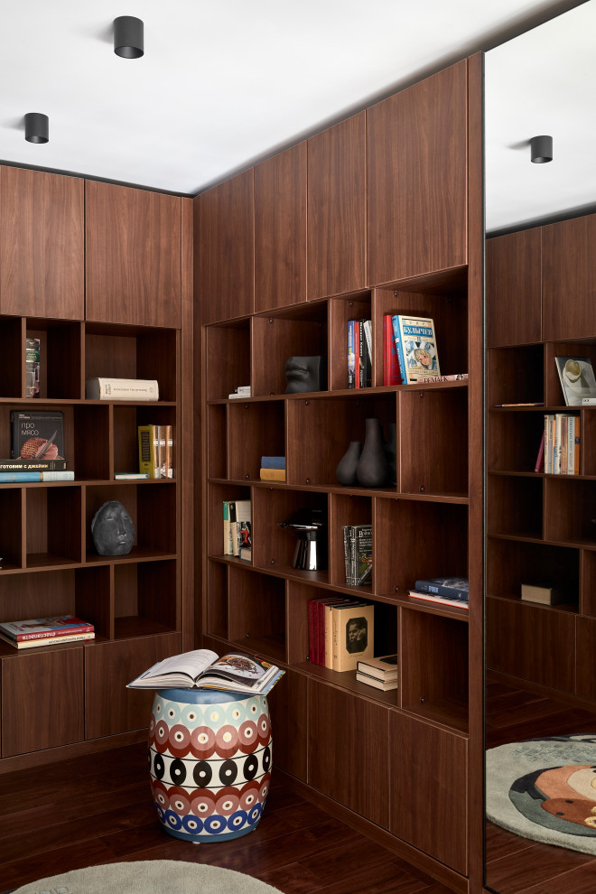На фото: гостиная комната в современном стиле с с книжными шкафами и полками и темным паркетным полом