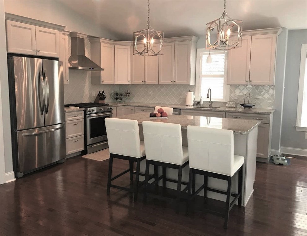 Mid-sized beach style open plan kitchen in Philadelphia with a single-bowl sink, shaker cabinets, grey cabinets, granite benchtops, white splashback, glass tile splashback, stainless steel appliances, medium hardwood floors, with island, brown floor and grey benchtop.