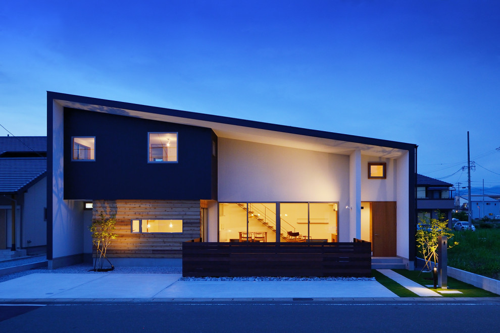 Стильный дизайн: большой, двухэтажный, белый частный загородный дом в скандинавском стиле с комбинированной облицовкой, односкатной крышей, металлической крышей, черной крышей и отделкой доской с нащельником - последний тренд