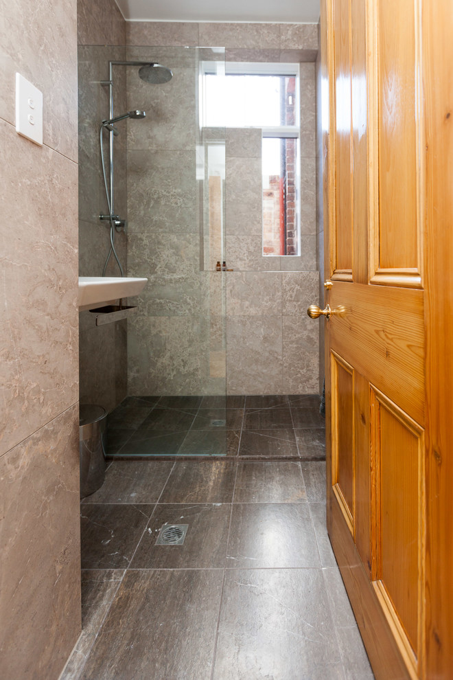 This is an example of a small traditional 3/4 bathroom in Melbourne with a wall-mount sink, glass-front cabinets, a wall-mount toilet, black tile, stone tile, beige walls and marble floors.