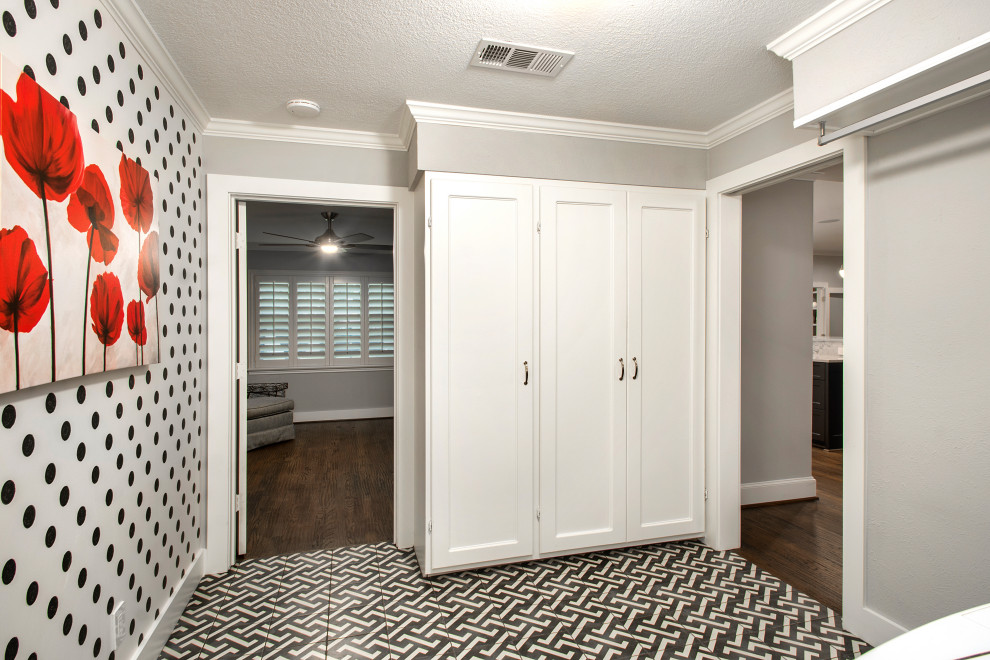 Design ideas for a mid-sized transitional l-shaped dedicated laundry room in Dallas with raised-panel cabinets, white cabinets, dark hardwood floors, a side-by-side washer and dryer, multi-coloured floor and wallpaper.