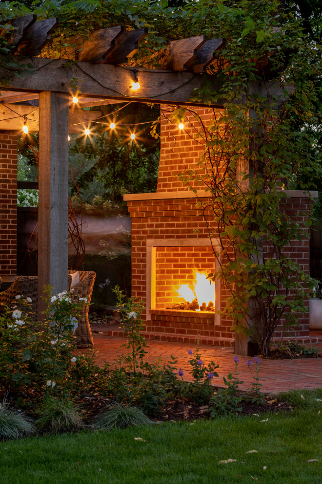Imagen de patio de estilo americano pequeño en patio trasero con chimenea, adoquines de ladrillo y pérgola