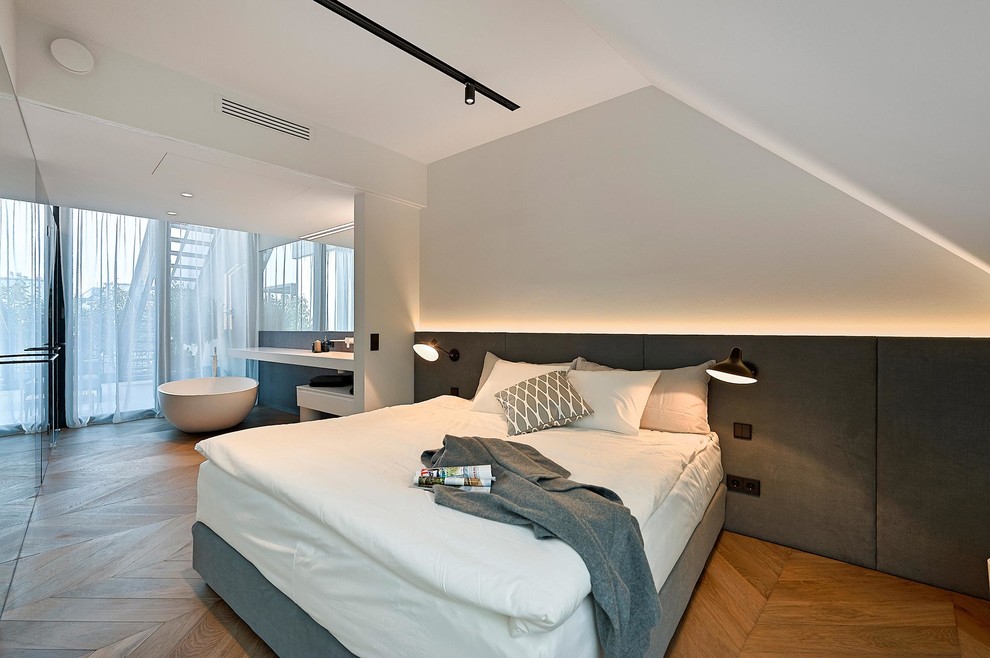 This is an example of a contemporary master bedroom in Naples with white walls and medium hardwood floors.