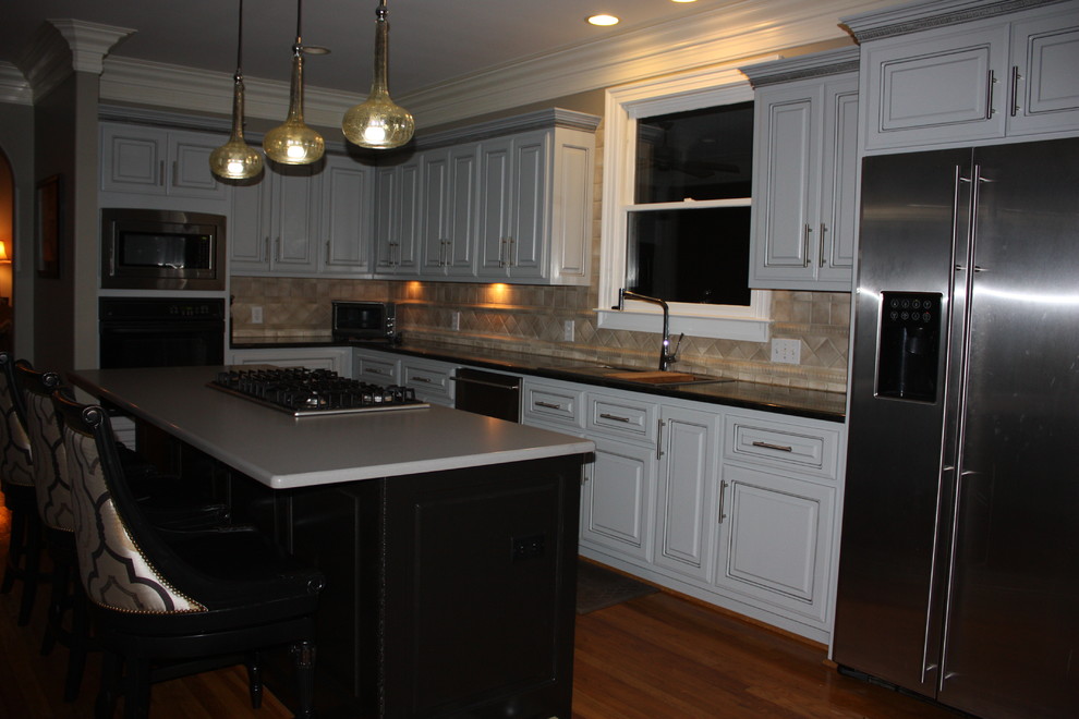Large transitional u-shaped light wood floor eat-in kitchen photo with a double-bowl sink, raised-panel cabinets, gray cabinets, quartz countertops, beige backsplash, ceramic backsplash, stainless steel appliances and an island