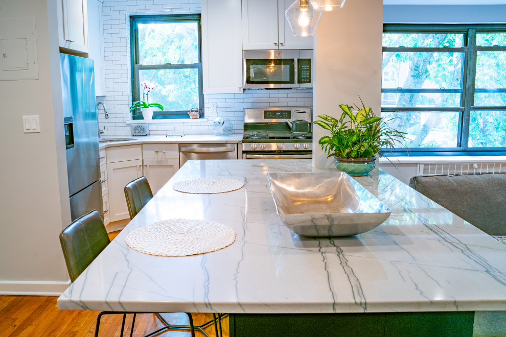 Small minimalist l-shaped medium tone wood floor and brown floor eat-in kitchen photo in New York with a single-bowl sink, shaker cabinets, black cabinets, quartzite countertops, white backsplash, subway tile backsplash, stainless steel appliances, an island and white countertops