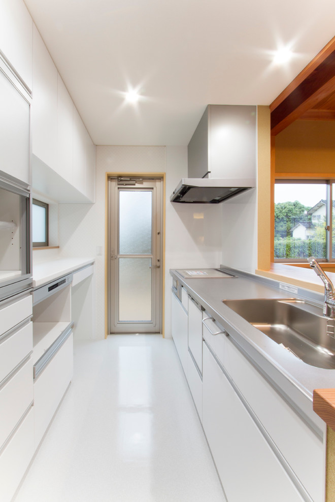 Photo of a mid-sized contemporary single-wall eat-in kitchen in Other with an integrated sink, white cabinets, stainless steel benchtops, white splashback, white appliances, vinyl floors, multiple islands, white floor and white benchtop.