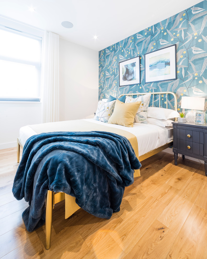 Contemporary bedroom in London with blue walls, light hardwood floors and beige floor.
