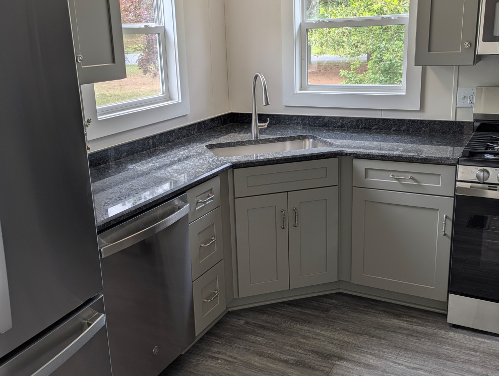 Inspiration for a small transitional l-shaped gray floor enclosed kitchen remodel with a single-bowl sink, flat-panel cabinets, gray cabinets, granite countertops, stainless steel appliances and black countertops