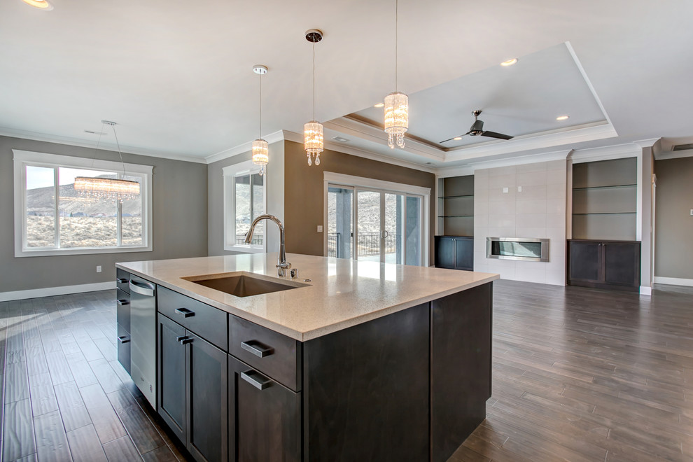 Inspiration for a large transitional l-shaped medium tone wood floor open concept kitchen remodel in Seattle with an undermount sink, shaker cabinets, white cabinets, glass countertops, gray backsplash, glass tile backsplash, stainless steel appliances and an island