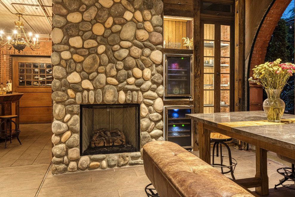 Photo of a medium sized traditional games room in Cedar Rapids with multi-coloured walls, light hardwood flooring, a standard fireplace, a home bar, a stone fireplace surround and brown floors.