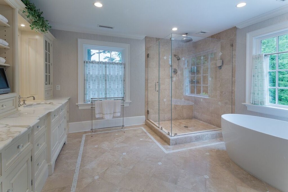 Large transitional master bathroom in New York with recessed-panel cabinets, white cabinets, a freestanding tub, an alcove shower, a two-piece toilet, beige tile, ceramic tile, grey walls, travertine floors, an undermount sink, marble benchtops, beige floor and a hinged shower door.