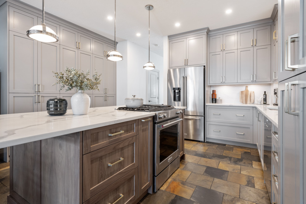 Inspiration for a mid-sized contemporary l-shaped eat-in kitchen in Calgary with an undermount sink, shaker cabinets, grey cabinets, quartz benchtops, white splashback, porcelain splashback, stainless steel appliances, slate floors, with island, multi-coloured floor and white benchtop.
