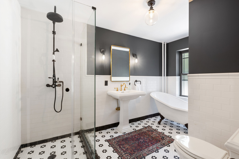Photo of a large contemporary cream and black ensuite bathroom in New York with a claw-foot bath, a two-piece toilet, white tiles, metro tiles, black walls, mosaic tile flooring, a pedestal sink, a hinged door and a single sink.
