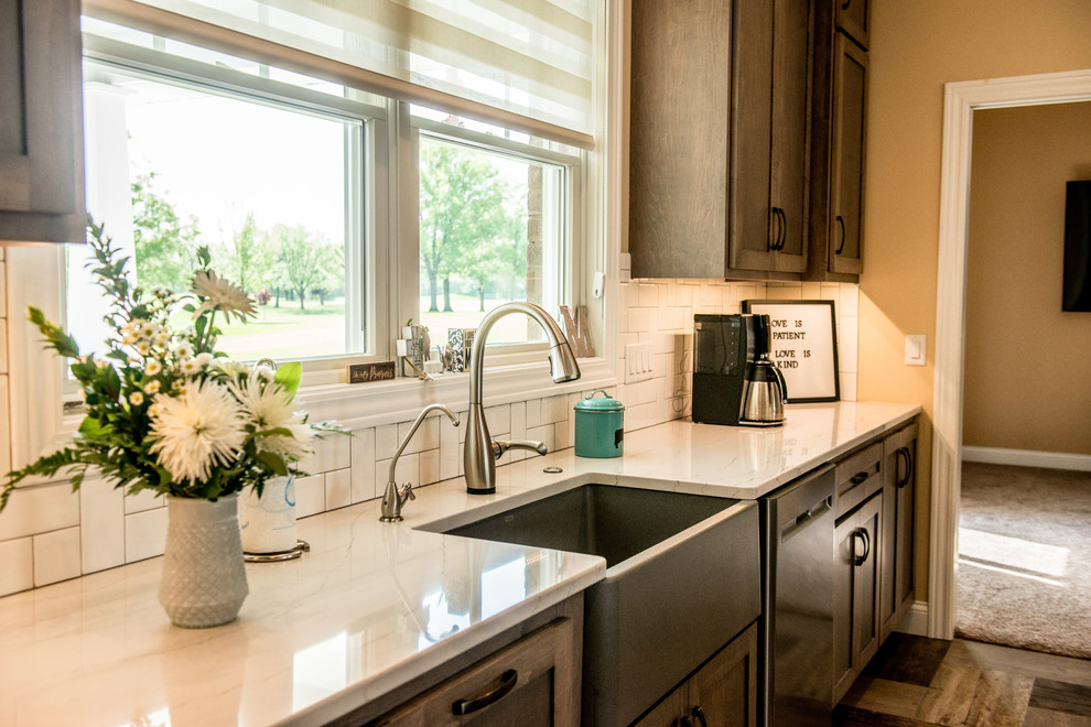 Large transitional l-shaped vinyl floor and multicolored floor open concept kitchen photo with a farmhouse sink, shaker cabinets, gray cabinets, quartz countertops, white backsplash, subway tile backsplash, stainless steel appliances, an island and white countertops