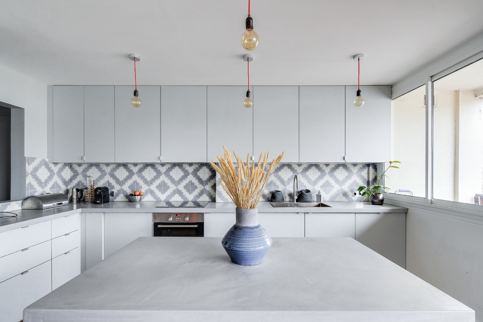 Idées déco pour une grande cuisine américaine contemporaine en L avec un évier encastré, un placard à porte affleurante, des portes de placard grises, un plan de travail en béton, une crédence grise, une crédence en carreau de ciment, un électroménager en acier inoxydable, îlot, un plan de travail gris, un sol en bois brun et un sol marron.