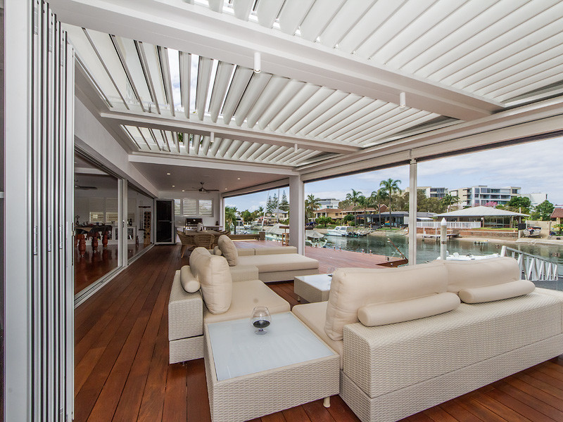 Photo of a large contemporary backyard deck in Brisbane with with dock and a roof extension.