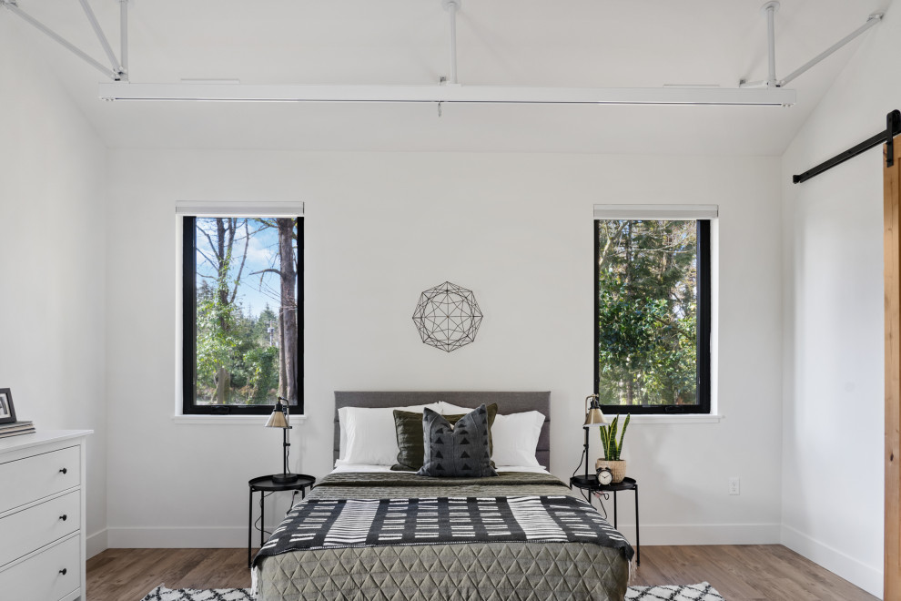 This is an example of a large contemporary bedroom in Portland with white walls and laminate floors.