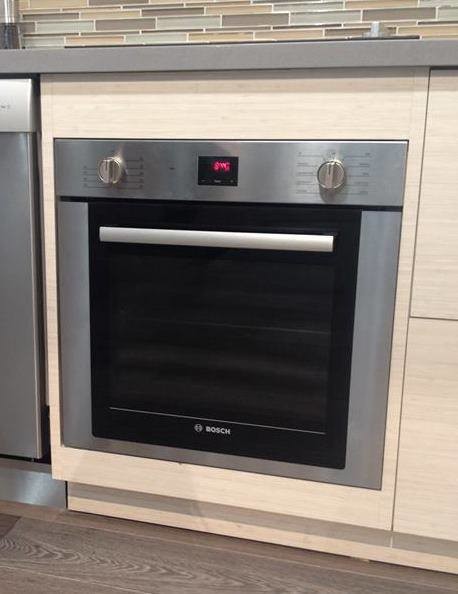 Inspiration for a small transitional dark wood floor enclosed kitchen remodel in Houston with flat-panel cabinets, solid surface countertops, glass tile backsplash, light wood cabinets, multicolored backsplash and stainless steel appliances