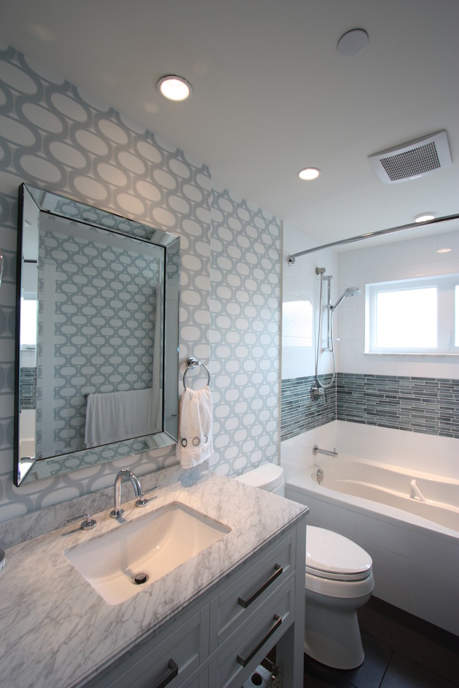 Photo of a small transitional bathroom in Vancouver with an undermount sink, shaker cabinets, white cabinets, marble benchtops, a shower/bathtub combo, a one-piece toilet, white tile, subway tile, white walls and porcelain floors.