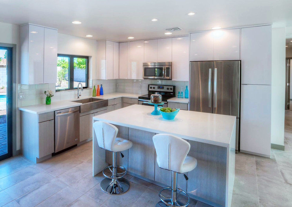 Photo of a mid-sized contemporary l-shaped open plan kitchen in Phoenix with a farmhouse sink, flat-panel cabinets, white cabinets, quartzite benchtops, white splashback, stainless steel appliances and with island.