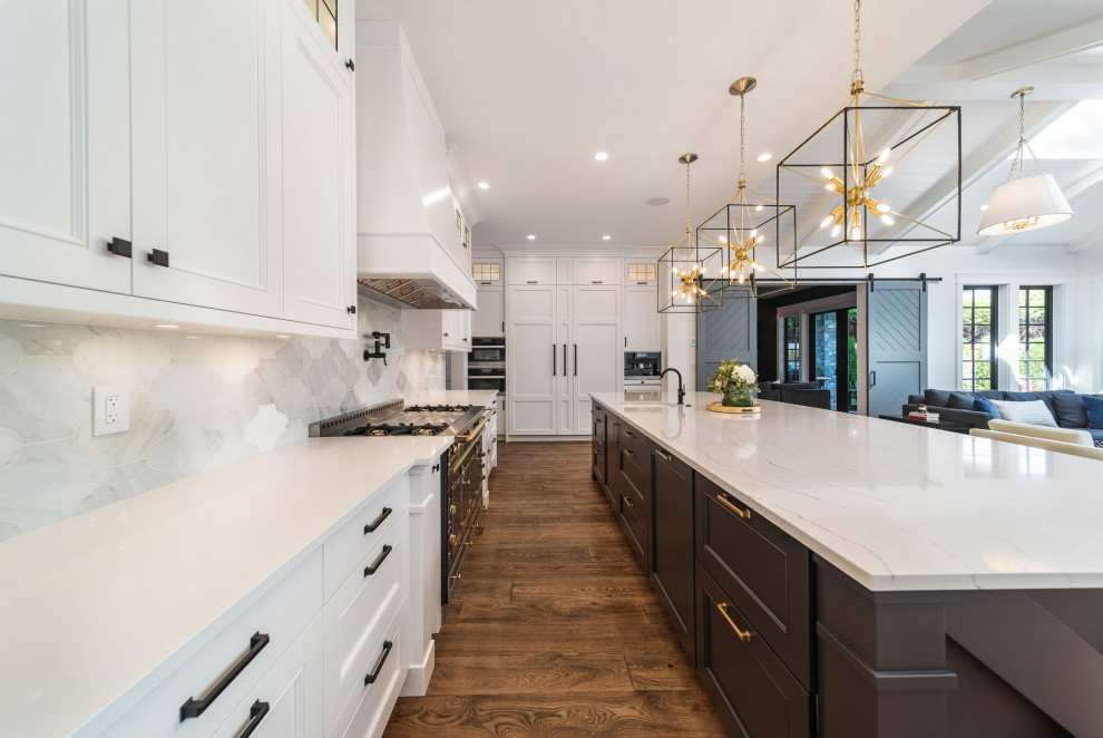 Open concept kitchen - large craftsman dark wood floor, brown floor and shiplap ceiling open concept kitchen idea in Vancouver with a farmhouse sink, shaker cabinets, white cabinets, quartz countertops, white backsplash, porcelain backsplash, black appliances, an island and white countertops