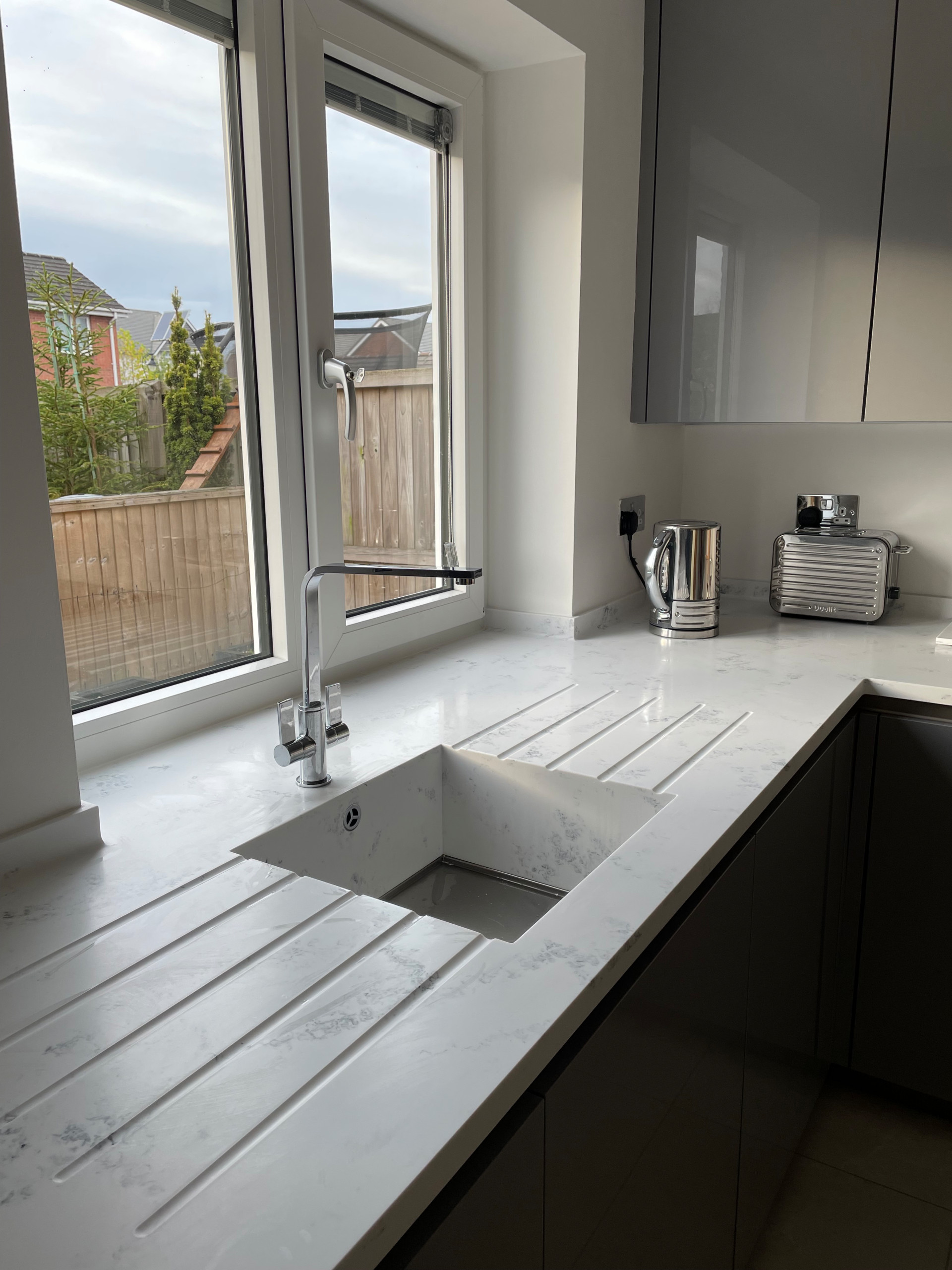 High Gloss Gravel Handleless Kitchen with White and Grey Solid Surface Tops