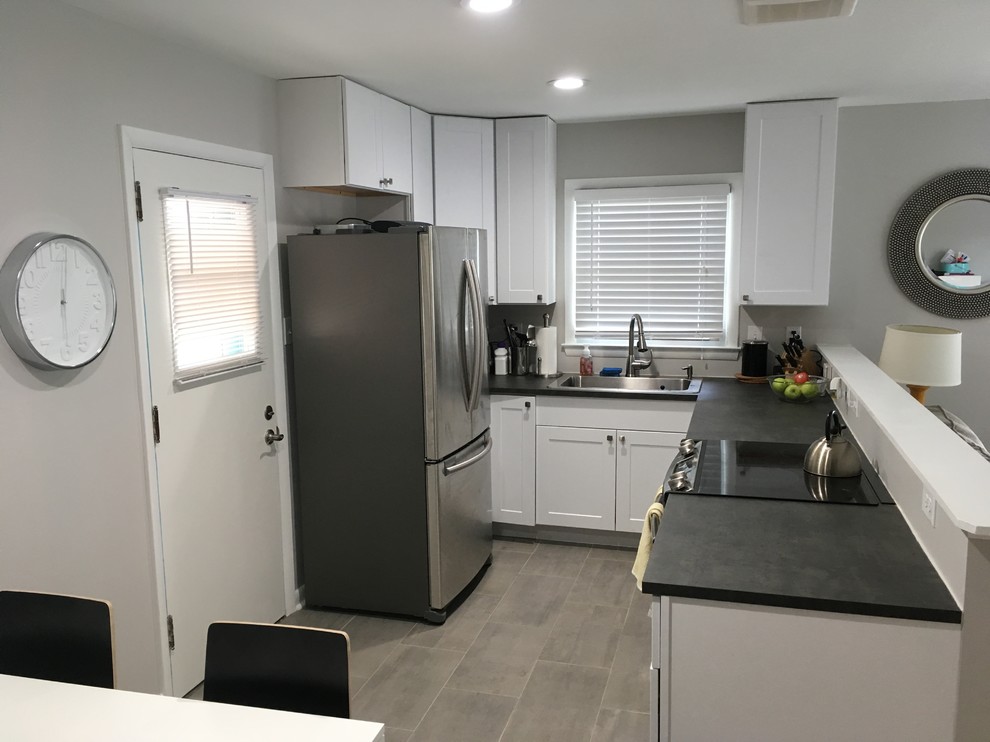 Small transitional u-shaped open plan kitchen in Other with a drop-in sink, shaker cabinets, white cabinets, soapstone benchtops, stainless steel appliances, porcelain floors, no island and grey floor.
