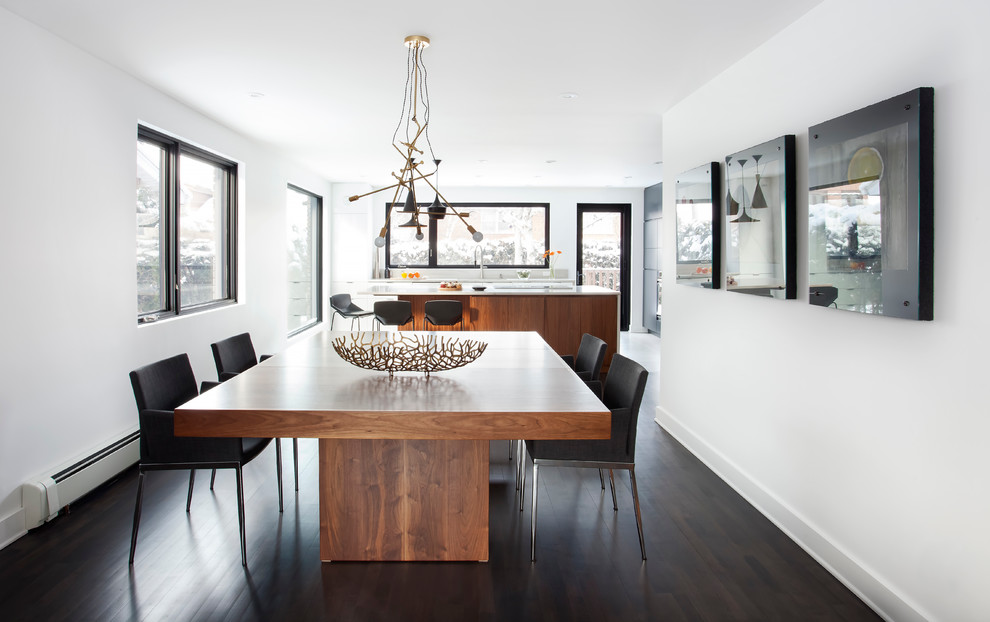 This is an example of a large contemporary dining room in Montreal with white walls, dark hardwood floors and brown floor.