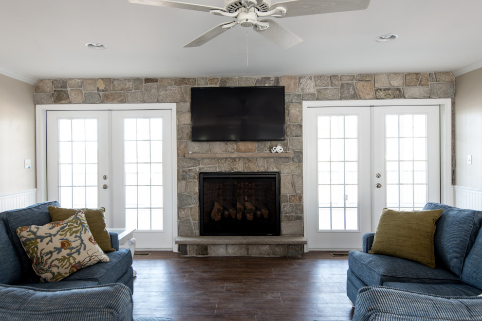 Design ideas for a large beach style open concept family room in Other with vinyl floors, a standard fireplace, a stone fireplace surround and a wall-mounted tv.