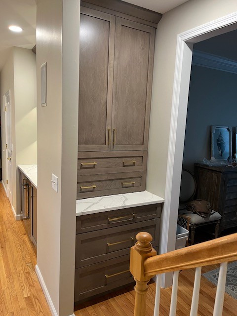 Large transitional l-shaped medium tone wood floor and brown floor eat-in kitchen photo in Boston with an undermount sink, shaker cabinets, white cabinets, quartz countertops, white backsplash, stainless steel appliances, an island and white countertops
