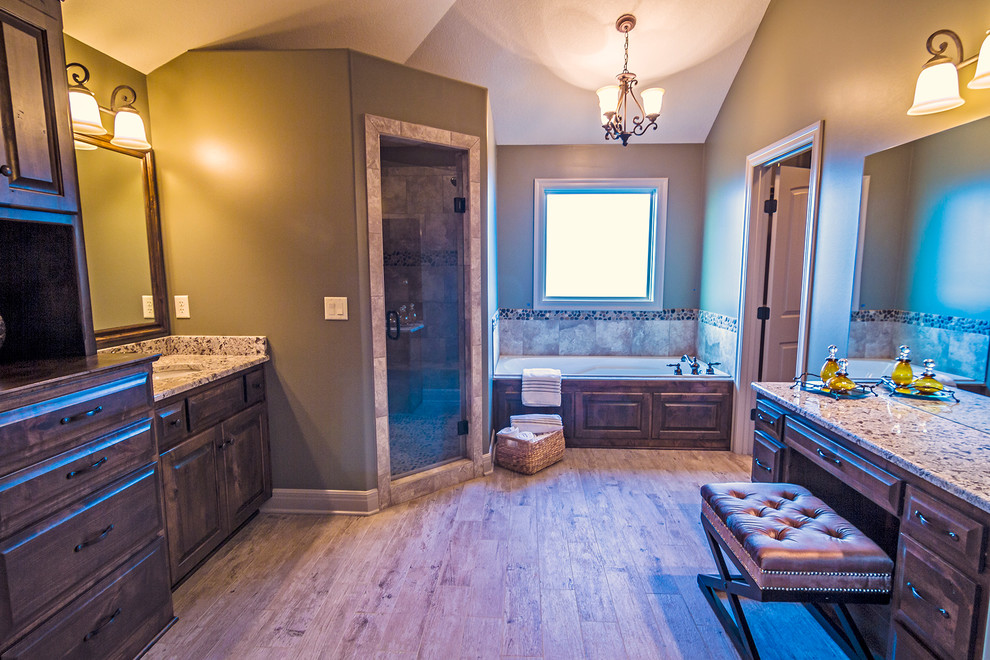 Design ideas for a large transitional master bathroom in Kansas City with an undermount sink, raised-panel cabinets, medium wood cabinets, granite benchtops, a corner shower, gray tile, ceramic tile, grey walls, ceramic floors, a corner tub and a hinged shower door.