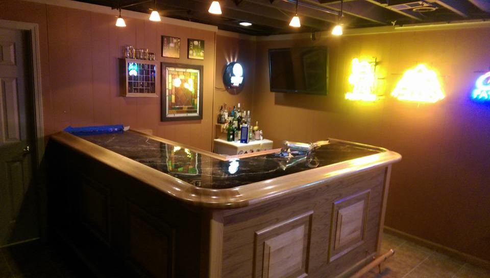 This is an example of a mid-sized country l-shaped wet bar in Cleveland with a drop-in sink, raised-panel cabinets, concrete benchtops and ceramic floors.
