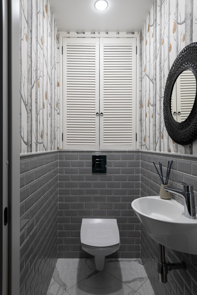 Small cloakroom in Moscow with louvered cabinets, white cabinets, grey tiles, metro tiles, grey walls, porcelain flooring, a wall-mounted sink, a floating vanity unit and wallpapered walls.