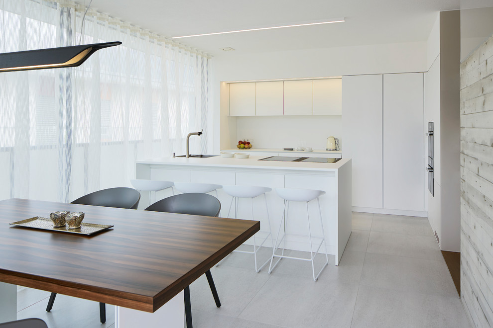 This is an example of a mid-sized modern galley eat-in kitchen in Other with flat-panel cabinets, white cabinets, laminate benchtops, black appliances, ceramic floors, with island, grey floor and white splashback.