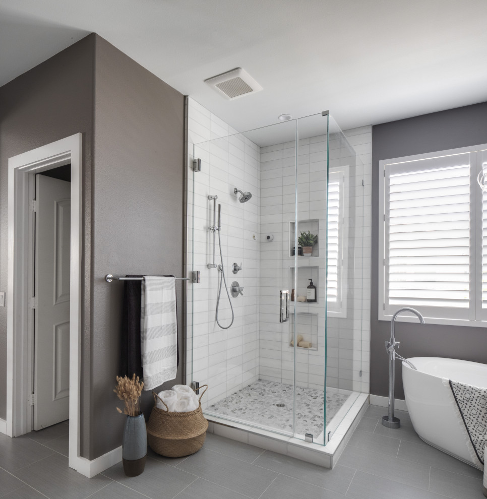 Design ideas for a mid-sized contemporary master bathroom in Orange County with flat-panel cabinets, grey cabinets, a freestanding tub, a corner shower, a two-piece toilet, white tile, marble, grey walls, porcelain floors, an undermount sink, engineered quartz benchtops, grey floor, a hinged shower door, white benchtops, an enclosed toilet, a double vanity and a built-in vanity.