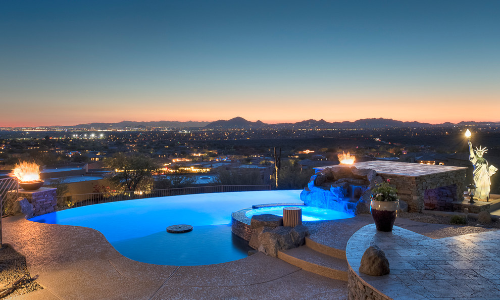 Design ideas for a large contemporary backyard custom-shaped infinity pool in Phoenix with a water feature and decking.