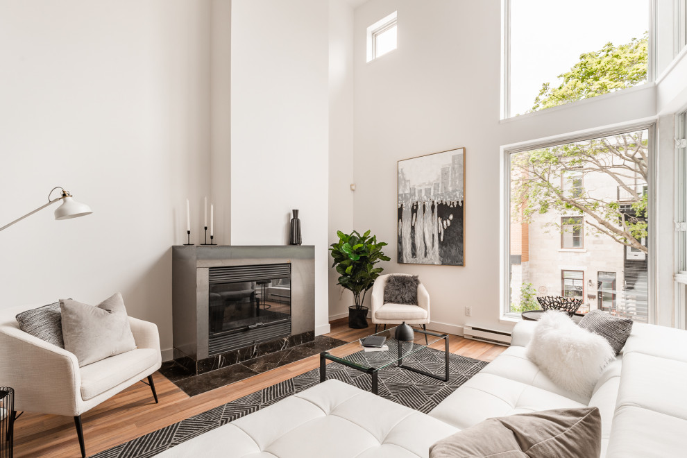 Photo of a large modern open concept living room in Montreal with white walls, medium hardwood floors, a standard fireplace, a metal fireplace surround, brown floor and vaulted.