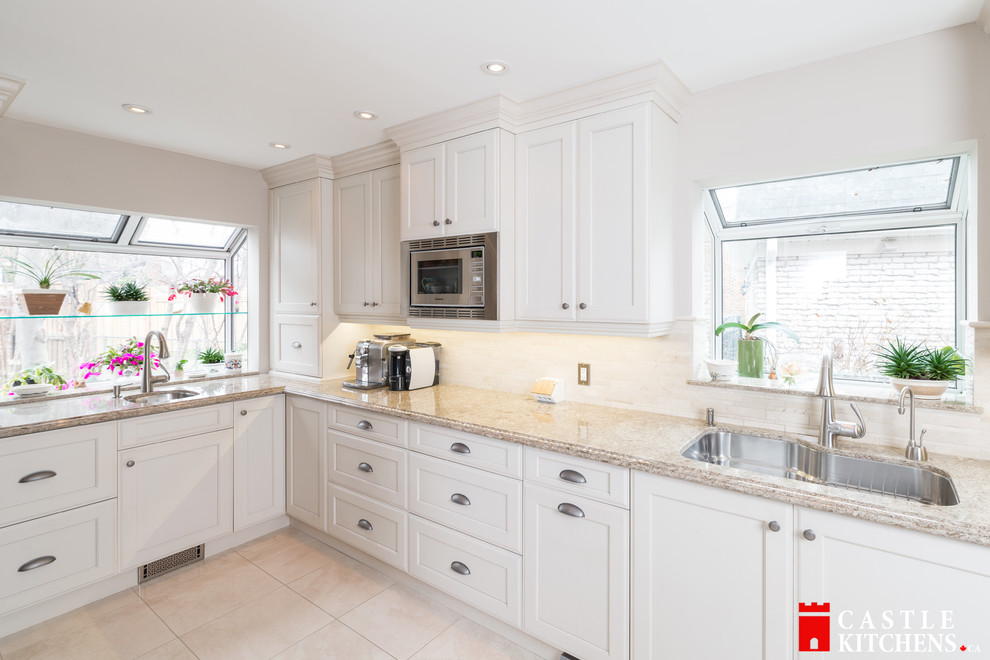 Example of a mid-sized transitional galley porcelain tile enclosed kitchen design in Toronto with an undermount sink, shaker cabinets, beige cabinets, quartzite countertops, beige backsplash, stainless steel appliances and an island