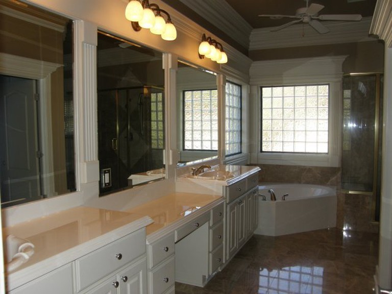 Example of a mid-sized transitional master corner bathtub design with flat-panel cabinets, white cabinets and a drop-in sink