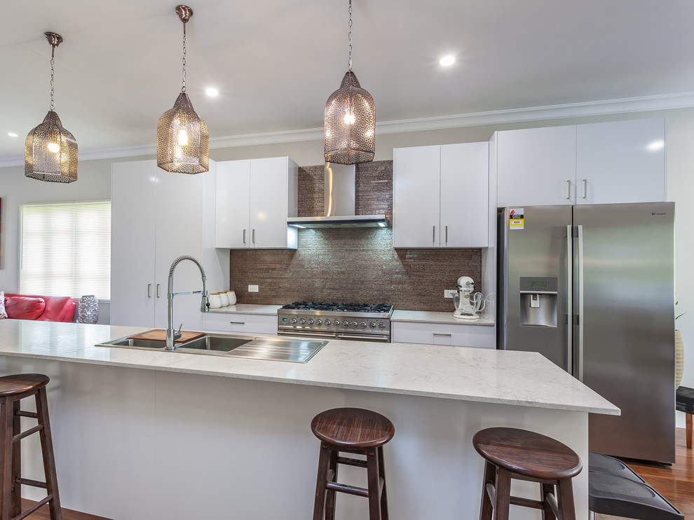Inspiration for a mid-sized modern galley eat-in kitchen in Brisbane with a drop-in sink, white cabinets, quartz benchtops, metallic splashback, matchstick tile splashback, stainless steel appliances, bamboo floors and with island.
