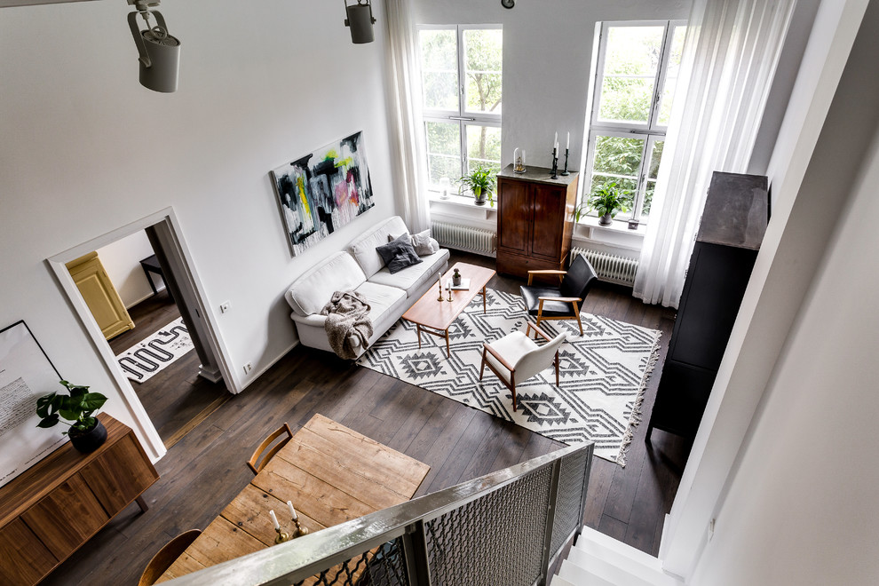Photo of a large scandinavian open concept living room in Stockholm with white walls and dark hardwood floors.