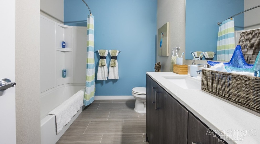 Mid-sized bathroom in Seattle with flat-panel cabinets, grey cabinets, an alcove tub, a shower/bathtub combo, blue walls, ceramic floors, an undermount sink and quartzite benchtops.