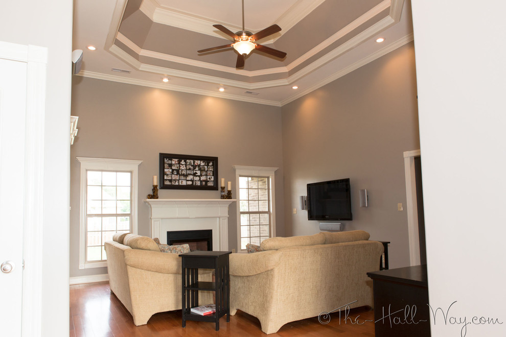 Large transitional enclosed family room in Other with grey walls, medium hardwood floors, a standard fireplace, a wood fireplace surround and a wall-mounted tv.