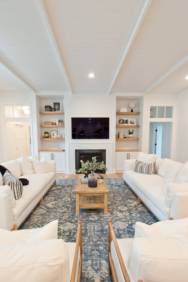 Exempel på ett klassiskt vardagsrum, med vita väggar, ljust trägolv, en standard öppen spis, en väggmonterad TV och brunt golv