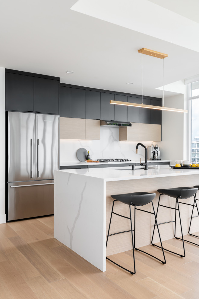 This is an example of a mid-sized contemporary single-wall eat-in kitchen in Vancouver with an undermount sink, flat-panel cabinets, grey cabinets, quartz benchtops, white splashback, engineered quartz splashback, stainless steel appliances, light hardwood floors, with island, beige floor and white benchtop.