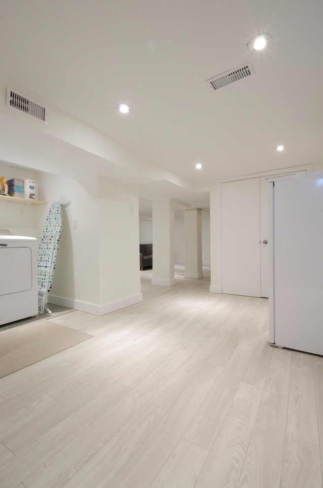 Basement - mid-sized transitional look-out laminate floor and beige floor basement idea in Toronto with white walls