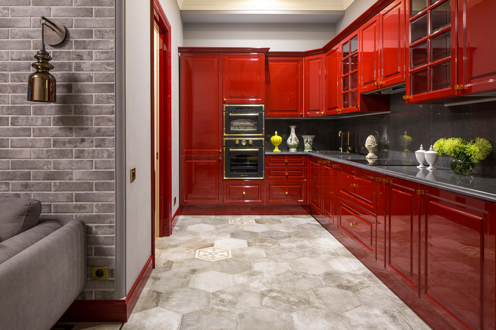 This is an example of a mid-sized traditional l-shaped open plan kitchen in Milan with raised-panel cabinets, red cabinets, granite benchtops, grey splashback, black appliances, porcelain floors and no island.