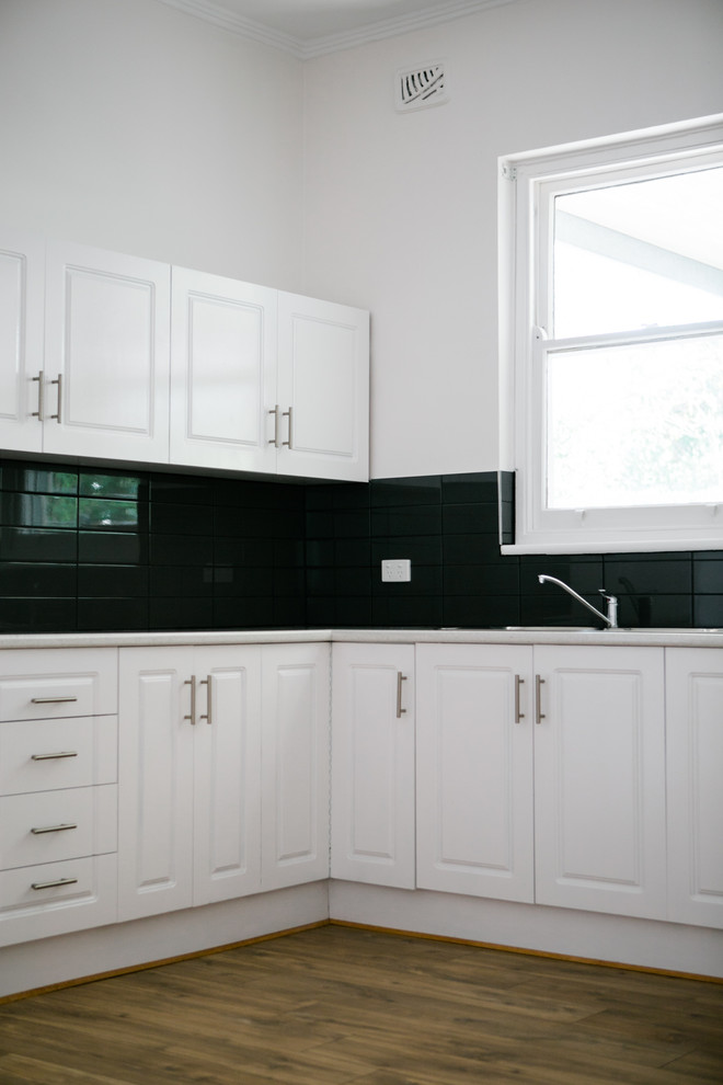 Inspiration for a mid-sized traditional u-shaped eat-in kitchen in Adelaide with a double-bowl sink, beaded inset cabinets, white cabinets, laminate benchtops, grey splashback, subway tile splashback, stainless steel appliances, laminate floors, brown floor and grey benchtop.
